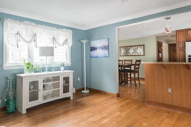 interior space with light wood-type flooring, baseboards, and crown molding