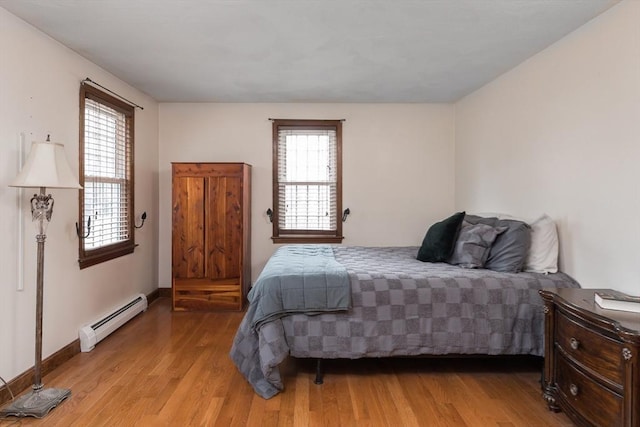 bedroom with a baseboard radiator, baseboards, and light wood-style flooring