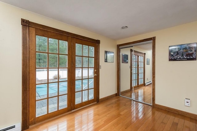 entryway with light wood-style flooring, a healthy amount of sunlight, baseboards, and a baseboard radiator