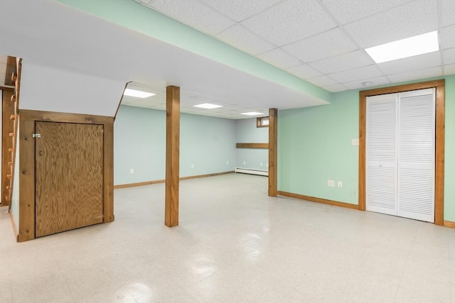 finished basement with tile patterned floors, a paneled ceiling, and baseboards