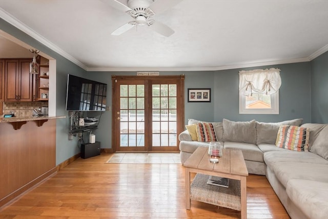 living room featuring baseboards, light wood finished floors, ceiling fan, french doors, and crown molding