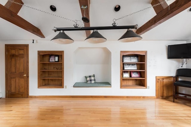 living room featuring built in shelves, lofted ceiling with beams, baseboards, and wood finished floors