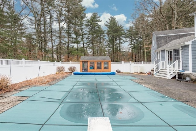 view of swimming pool with an outbuilding, a diving board, a fenced backyard, and a fenced in pool