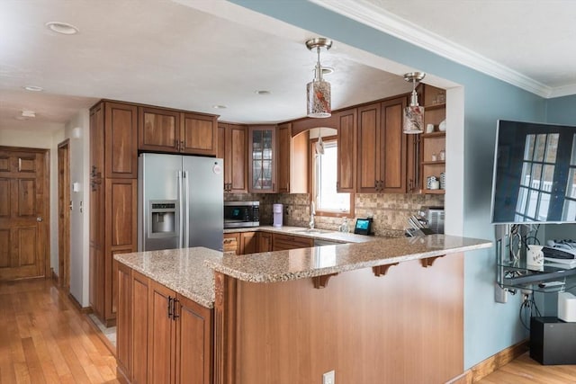 kitchen featuring a peninsula, decorative backsplash, appliances with stainless steel finishes, crown molding, and brown cabinets