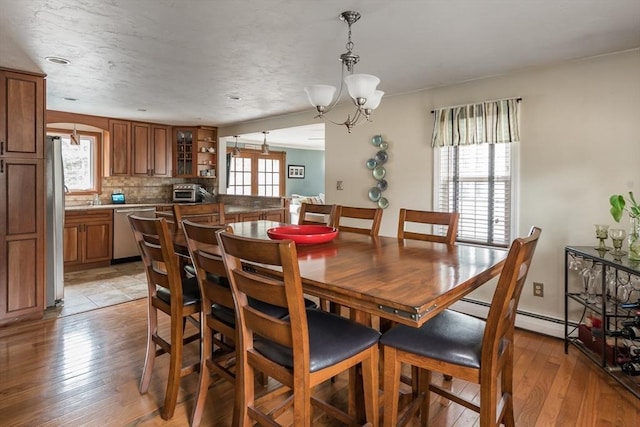 dining room with a chandelier, a healthy amount of sunlight, and light wood-style floors