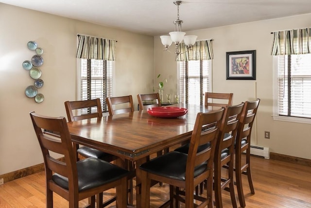 dining area with a wealth of natural light, a baseboard heating unit, and light wood-type flooring