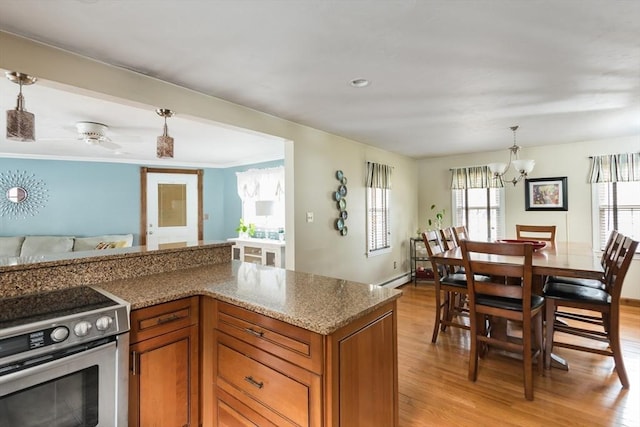 kitchen with brown cabinetry, electric stove, light wood-style floors, decorative light fixtures, and open floor plan