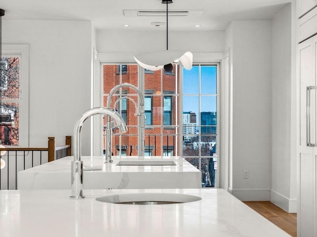 details featuring decorative light fixtures, a city view, a sink, light wood-type flooring, and baseboards