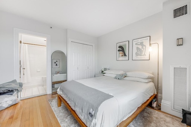 bedroom featuring a closet, light wood-style flooring, visible vents, and connected bathroom