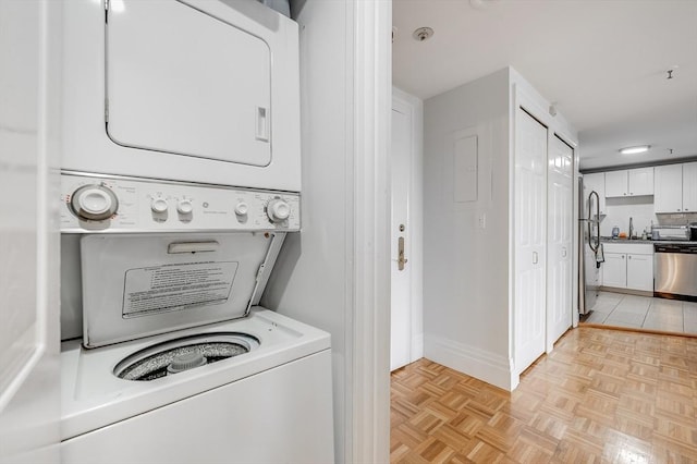 laundry area with laundry area, stacked washing maching and dryer, and baseboards