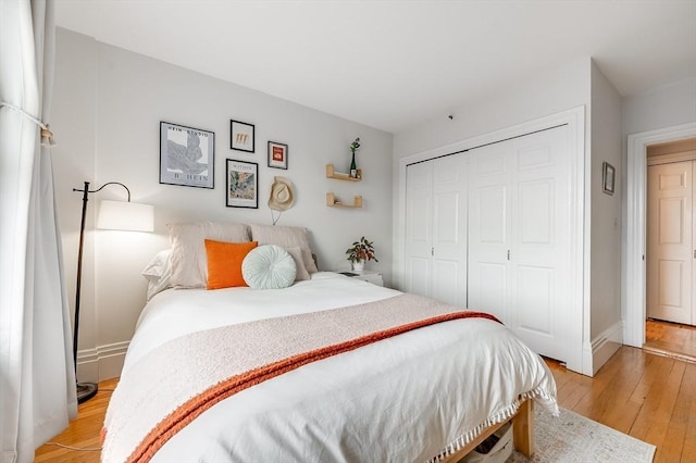 bedroom with a closet, light wood-style flooring, and baseboards
