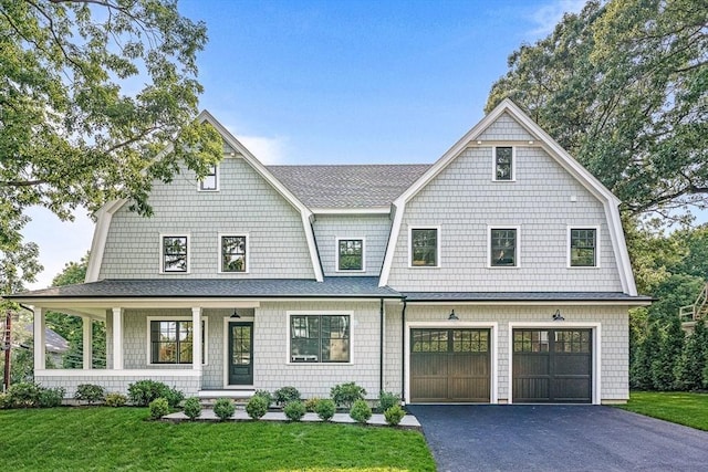 shingle-style home featuring an attached garage, a front yard, aphalt driveway, and a gambrel roof