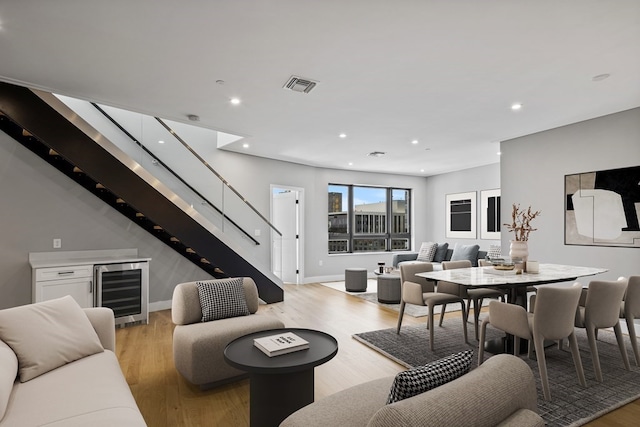 living room with light wood-type flooring, wine cooler, and bar