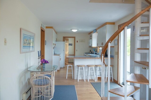 99 N Shore Blvd Unit 1, Sandwich, MA 02537 - kitchen with light wood-style floors, white appliances, a kitchen bar, a peninsula, and white cabinetry