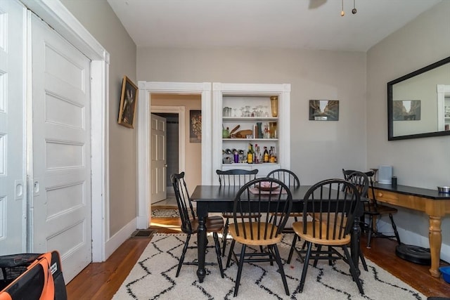 dining room with built in features and dark hardwood / wood-style flooring