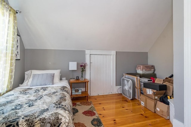 bedroom with vaulted ceiling and light wood-type flooring