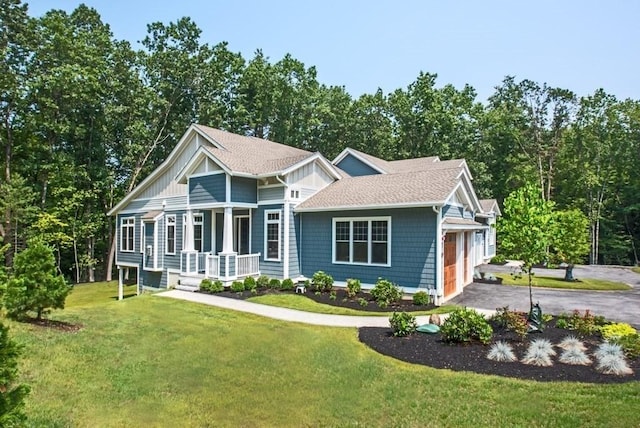 view of front of property with covered porch, a front yard, and a garage