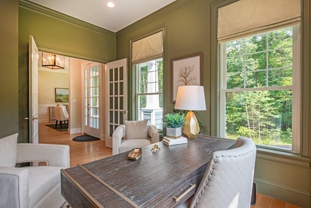 sitting room featuring a chandelier, light hardwood / wood-style flooring, a healthy amount of sunlight, and crown molding