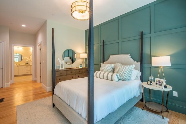 bedroom with ensuite bathroom and light hardwood / wood-style flooring