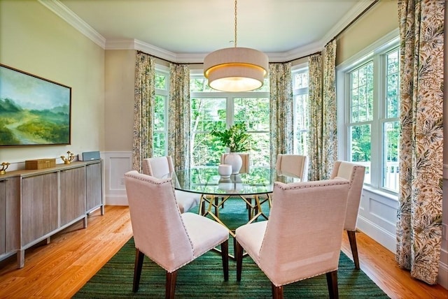 dining space featuring plenty of natural light, ornamental molding, and light hardwood / wood-style flooring