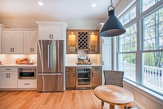 kitchen with white cabinets, appliances with stainless steel finishes, beverage cooler, and pendant lighting