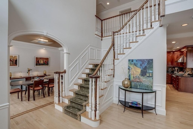 stairway featuring a decorative wall, wood finished floors, and ornamental molding