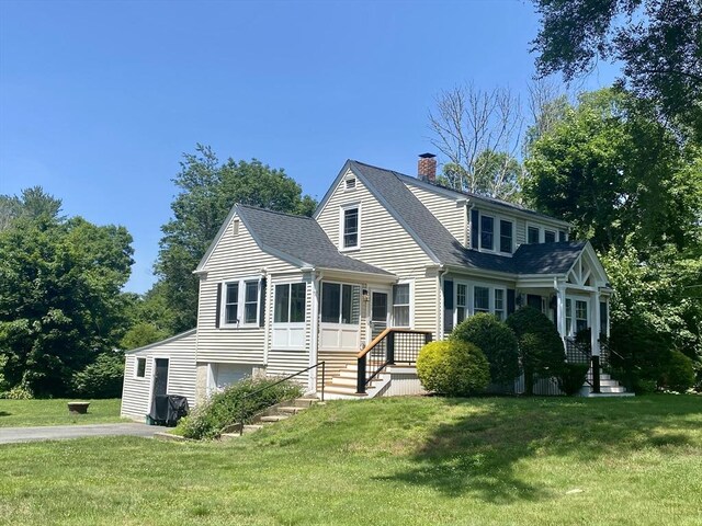 551 Indian Head St, Hanson, MA 02341 - view of front of home with a front yard, a shingled roof, a chimney, and driveway