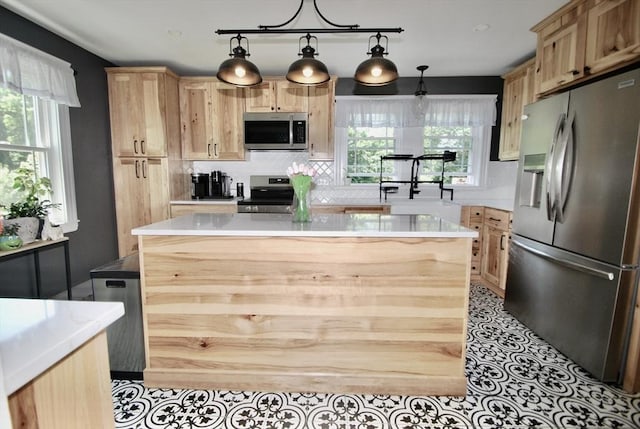 551 Indian Head St, Hanson, MA 02341 - kitchen with stainless steel appliances, light brown cabinets, light countertops, backsplash, and decorative light fixtures
