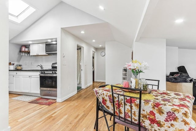 831 N Shore Rd, Revere, MA 02151 - kitchen featuring appliances with stainless steel finishes, a skylight, dark countertops, white cabinets, and light wood-style flooring