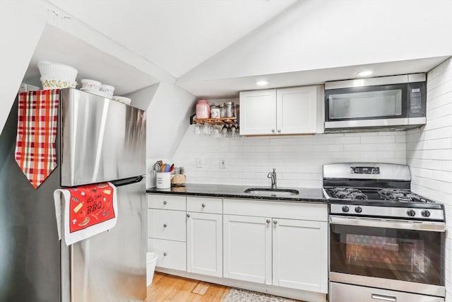 831 N Shore Rd, Revere, MA 02151 - kitchen with stainless steel appliances, a sink, lofted ceiling, dark stone counters, and tasteful backsplash