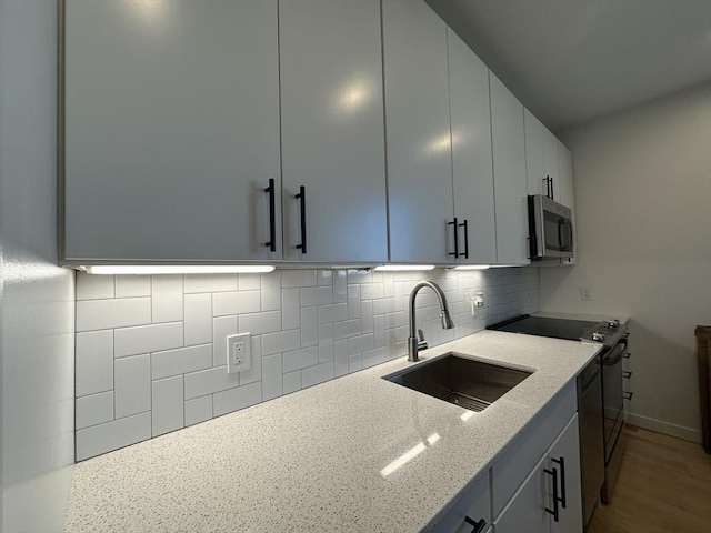 kitchen featuring tasteful backsplash, light stone counters, sink, and stainless steel appliances