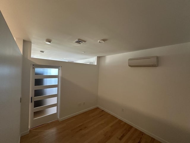 spare room featuring a wall mounted air conditioner and hardwood / wood-style flooring