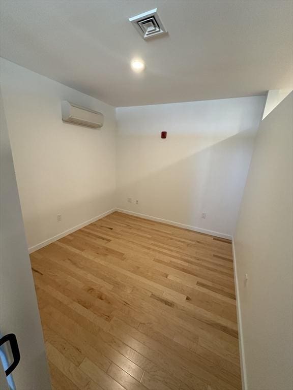 basement featuring an AC wall unit and light wood-type flooring