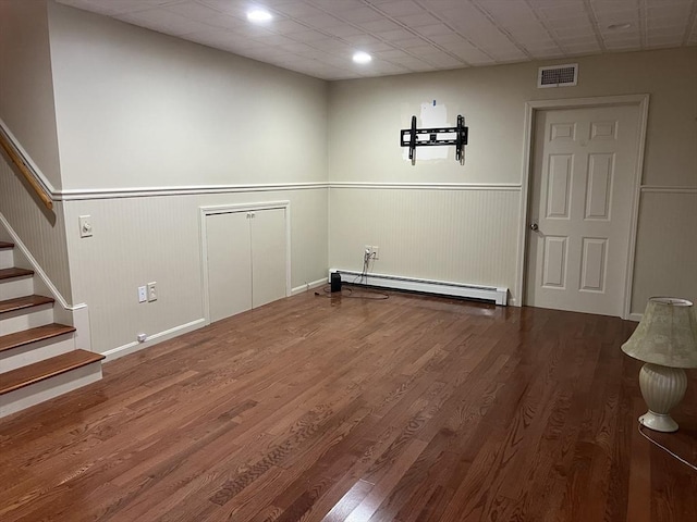 clothes washing area with hardwood / wood-style flooring and baseboard heating