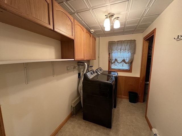 laundry room with cabinets, independent washer and dryer, and wood walls