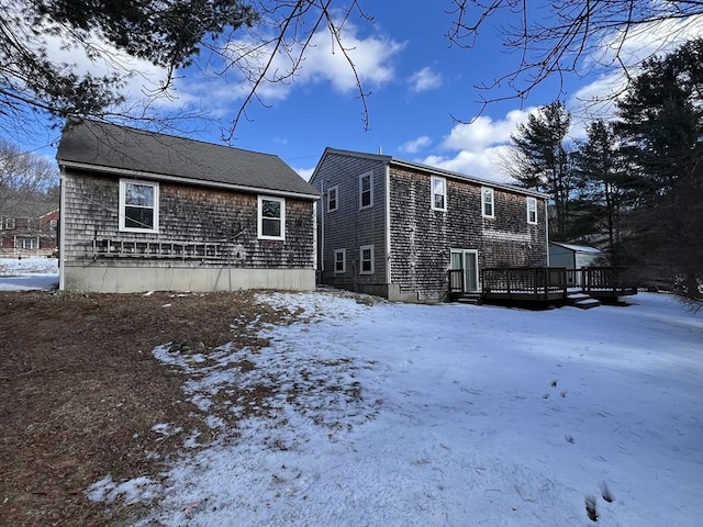 snow covered rear of property with a deck