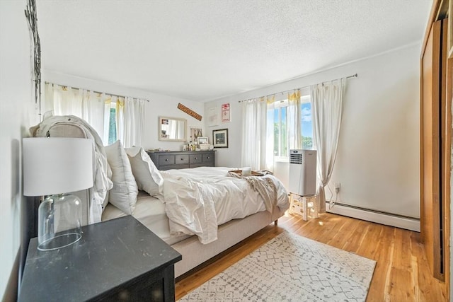 80 Main St Unit 20, Malden, MA 02148 - bedroom with baseboard heating, light wood finished floors, and a textured ceiling