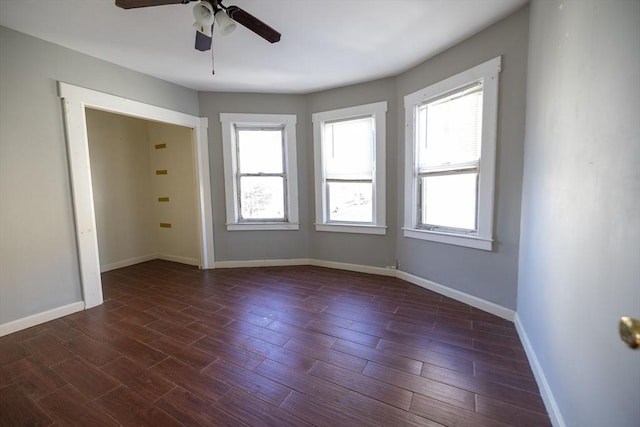 spare room with dark hardwood / wood-style floors, ceiling fan, and a healthy amount of sunlight