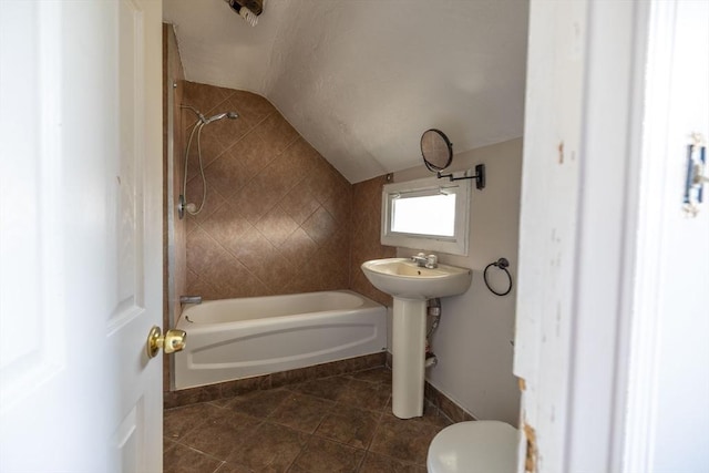 full bathroom featuring lofted ceiling, tile patterned floors, sink, tiled shower / bath combo, and toilet