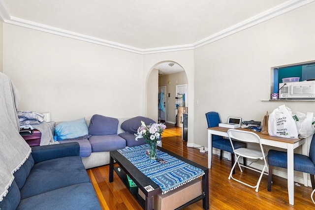 living area featuring arched walkways, crown molding, baseboards, and wood finished floors