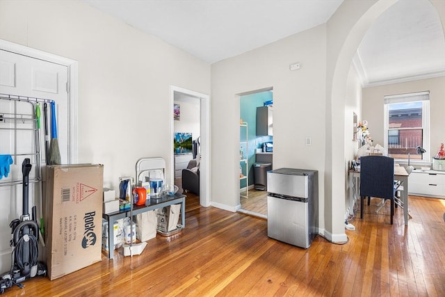 interior space featuring arched walkways, baseboards, and hardwood / wood-style floors