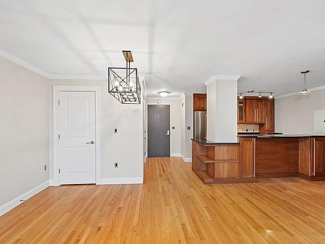 kitchen featuring light wood-type flooring, brown cabinets, ornamental molding, and freestanding refrigerator