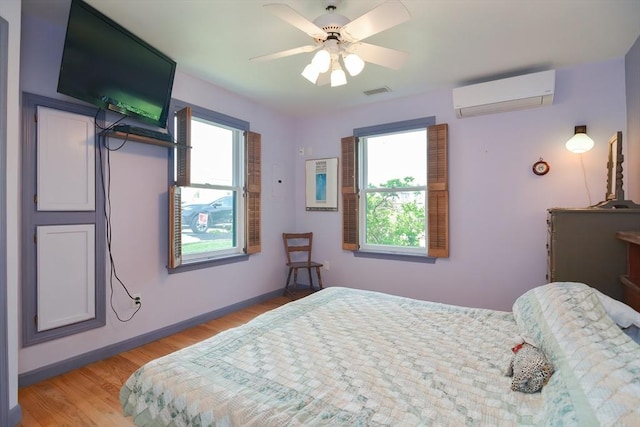 bedroom featuring ceiling fan, light wood-type flooring, an AC wall unit, and multiple windows