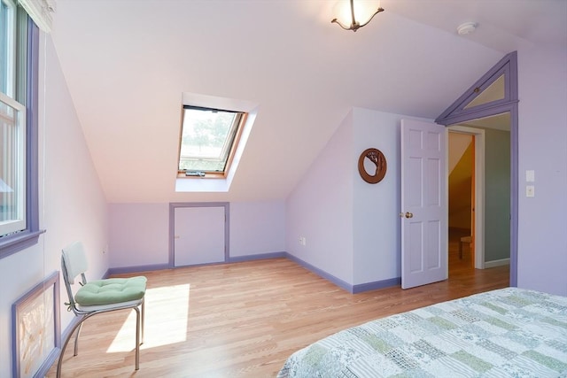 bedroom featuring light wood-type flooring and vaulted ceiling with skylight