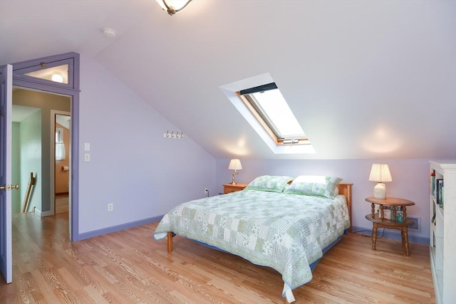 bedroom with lofted ceiling with skylight and light hardwood / wood-style floors