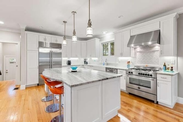 38 Paul Revere Rd, Lexington, MA 02421 - kitchen with high end appliances, exhaust hood, white cabinets, a kitchen island, and light wood-style floors