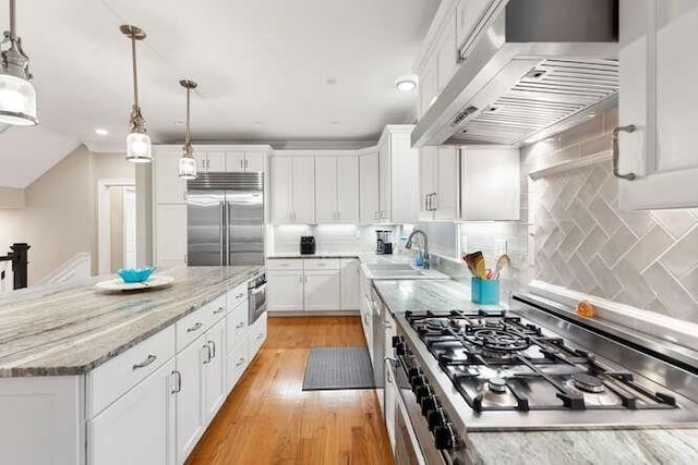 38 Paul Revere Rd, Lexington, MA 02421 - kitchen featuring wall chimney range hood, stainless steel built in refrigerator, stovetop, a sink, and white cabinets