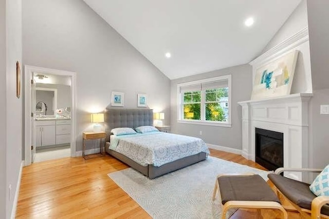 38 Paul Revere Rd, Lexington, MA 02421 - bedroom featuring light wood-style floors, a glass covered fireplace, high vaulted ceiling, baseboards, and connected bathroom