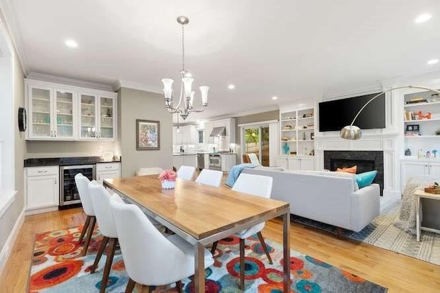 38 Paul Revere Rd, Lexington, MA 02421 - dining space featuring beverage cooler, light wood finished floors, a fireplace, a chandelier, and crown molding