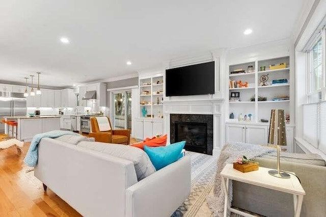 38 Paul Revere Rd, Lexington, MA 02421 - living room with healthy amount of natural light, light wood finished floors, a glass covered fireplace, ornamental molding, and recessed lighting